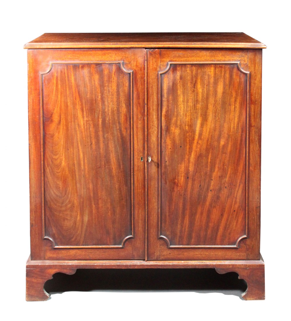 An 18th-century George III flame mahogany cupboard with two panelled doors, brass escutcheon, and a shaped bracket foot base.