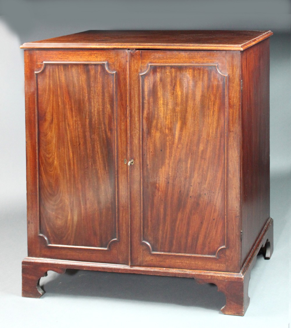 An 18th-century George III flame mahogany cupboard with two panelled doors, brass escutcheon, and a shaped bracket foot base. View II