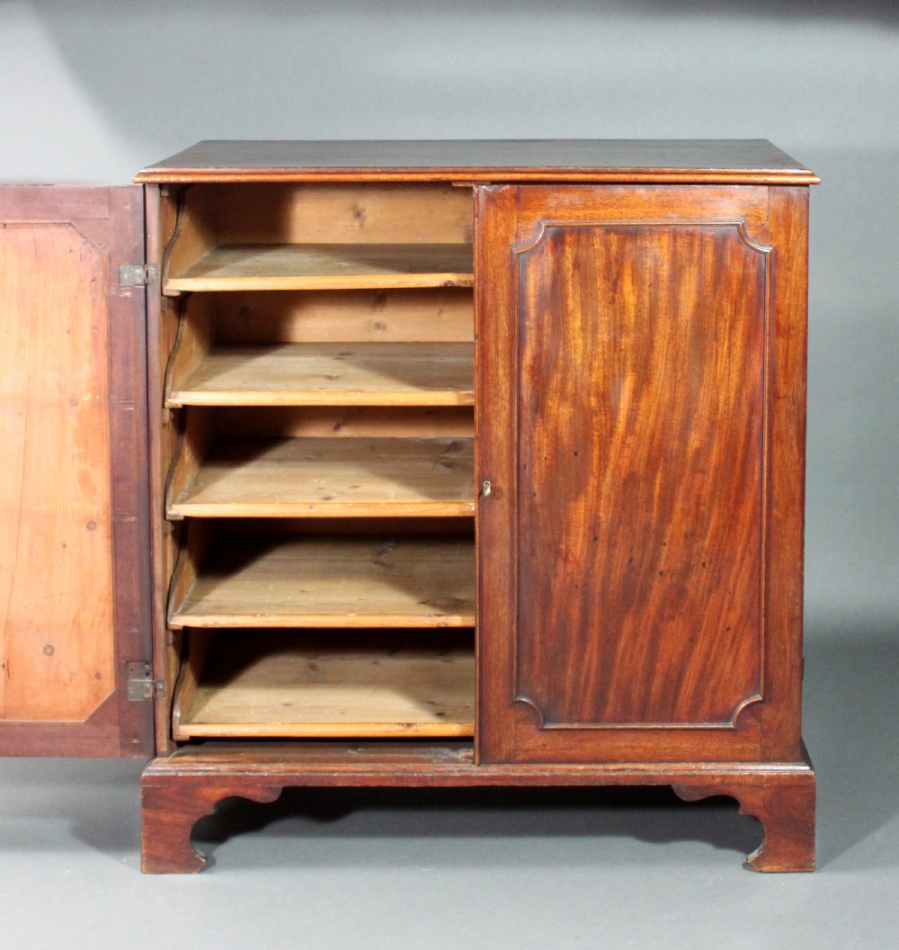An 18th-century George III flame mahogany cupboard with two panelled doors, brass escutcheon, and a shaped bracket foot base. View III