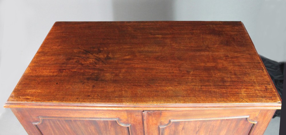 An 18th-century George III flame mahogany cupboard with two panelled doors, brass escutcheon, and a shaped bracket foot base. View IV