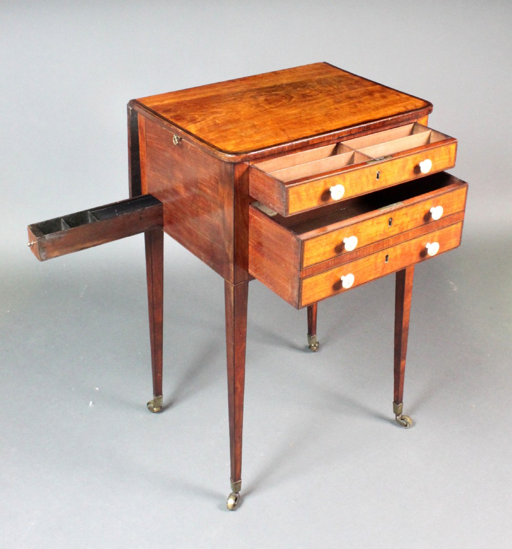 A George III satinwood sewing table featuring three drawers with bone knobs, hinged drop leaves, and square tapered legs on brass castors. View IV