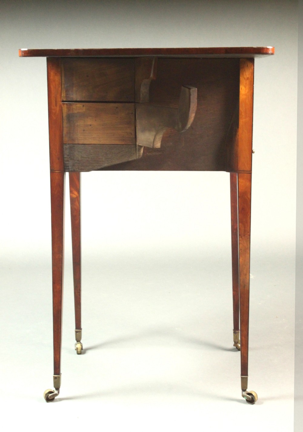 A George III satinwood sewing table featuring three drawers with bone knobs, hinged drop leaves, and square tapered legs on brass castors. View VII