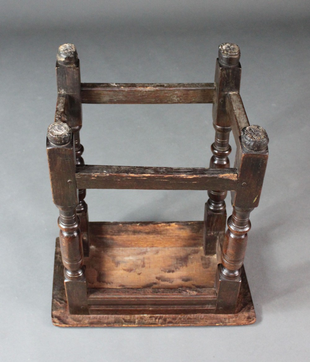 A seventeenth-century dark oak joined stool with turned legs, perimeter stretchers, and a moulded rectangular top. View V