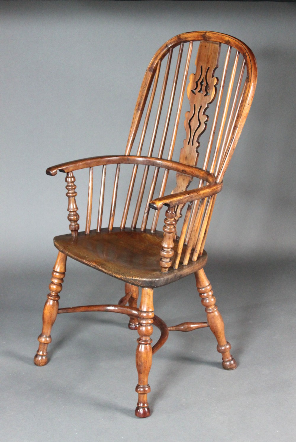 An antique high-back yew wood Windsor armchair featuring a pierced decorative splat, spindle backrest, turned legs, and a curved crinoline stretcher. View II