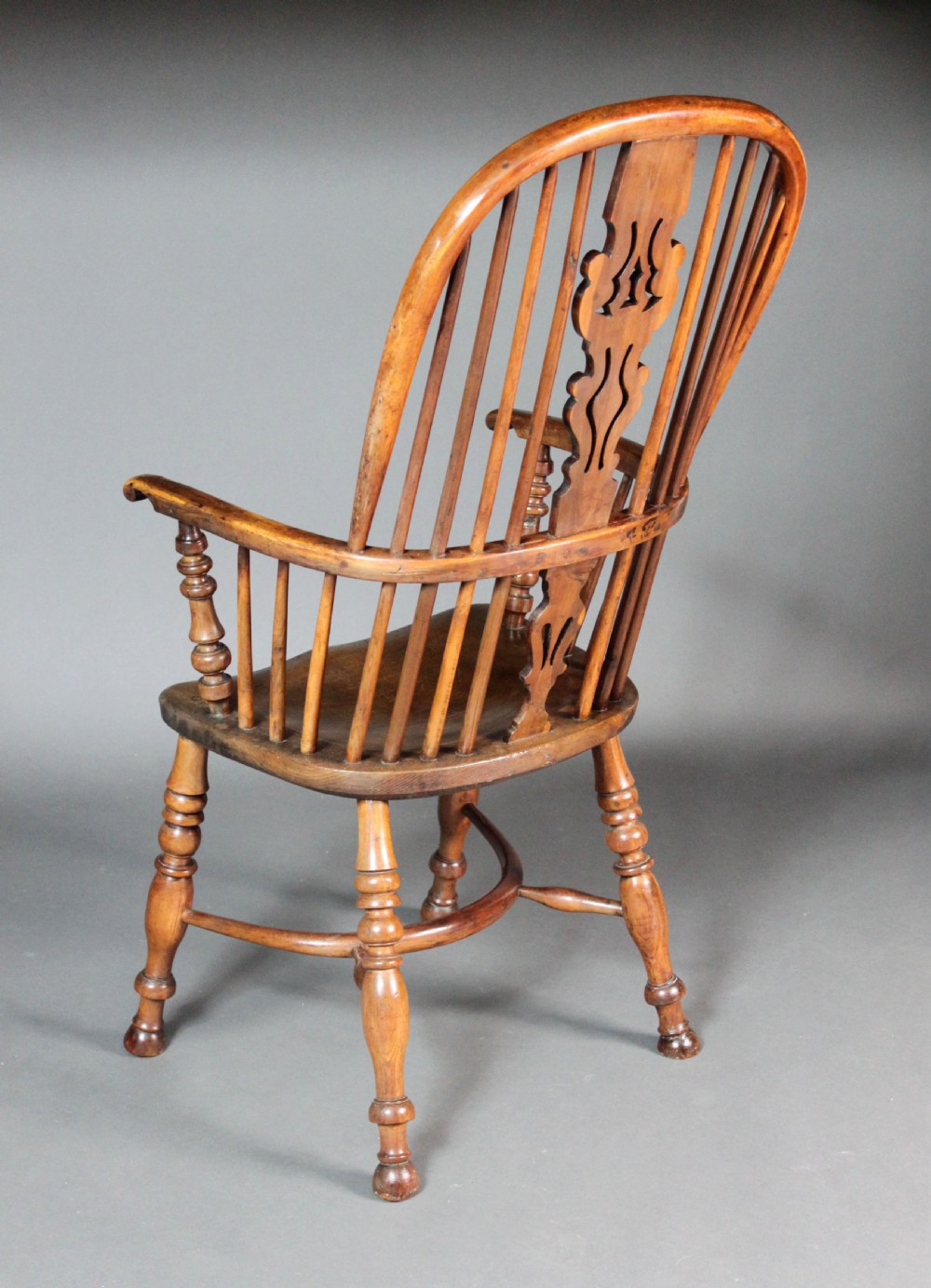 An antique high-back yew wood Windsor armchair featuring a pierced decorative splat, spindle backrest, turned legs, and a curved crinoline stretcher. View III