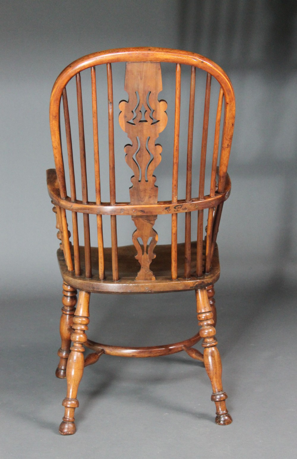 An antique high-back yew wood Windsor armchair featuring a pierced decorative splat, spindle backrest, turned legs, and a curved crinoline stretcher. View IV