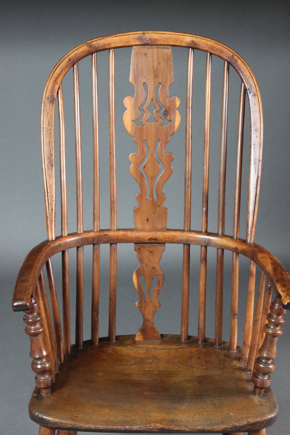 An antique high-back yew wood Windsor armchair featuring a pierced decorative splat, spindle backrest, turned legs, and a curved crinoline stretcher. View V