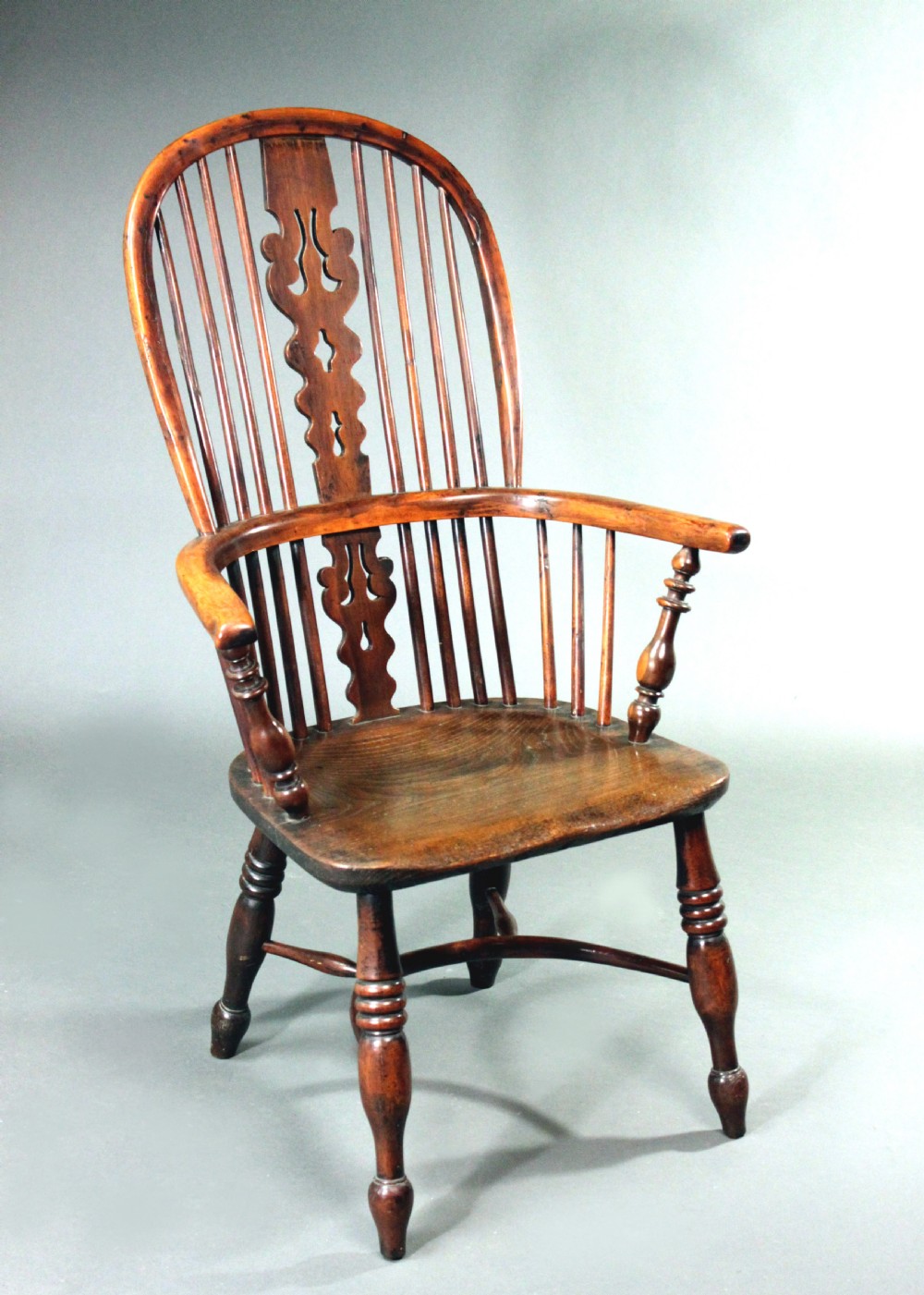 An antique yew wood Windsor armchair featuring a high bow back with vertical spindles, a pierced central splat, turned arm supports, and a shaped seat. View II