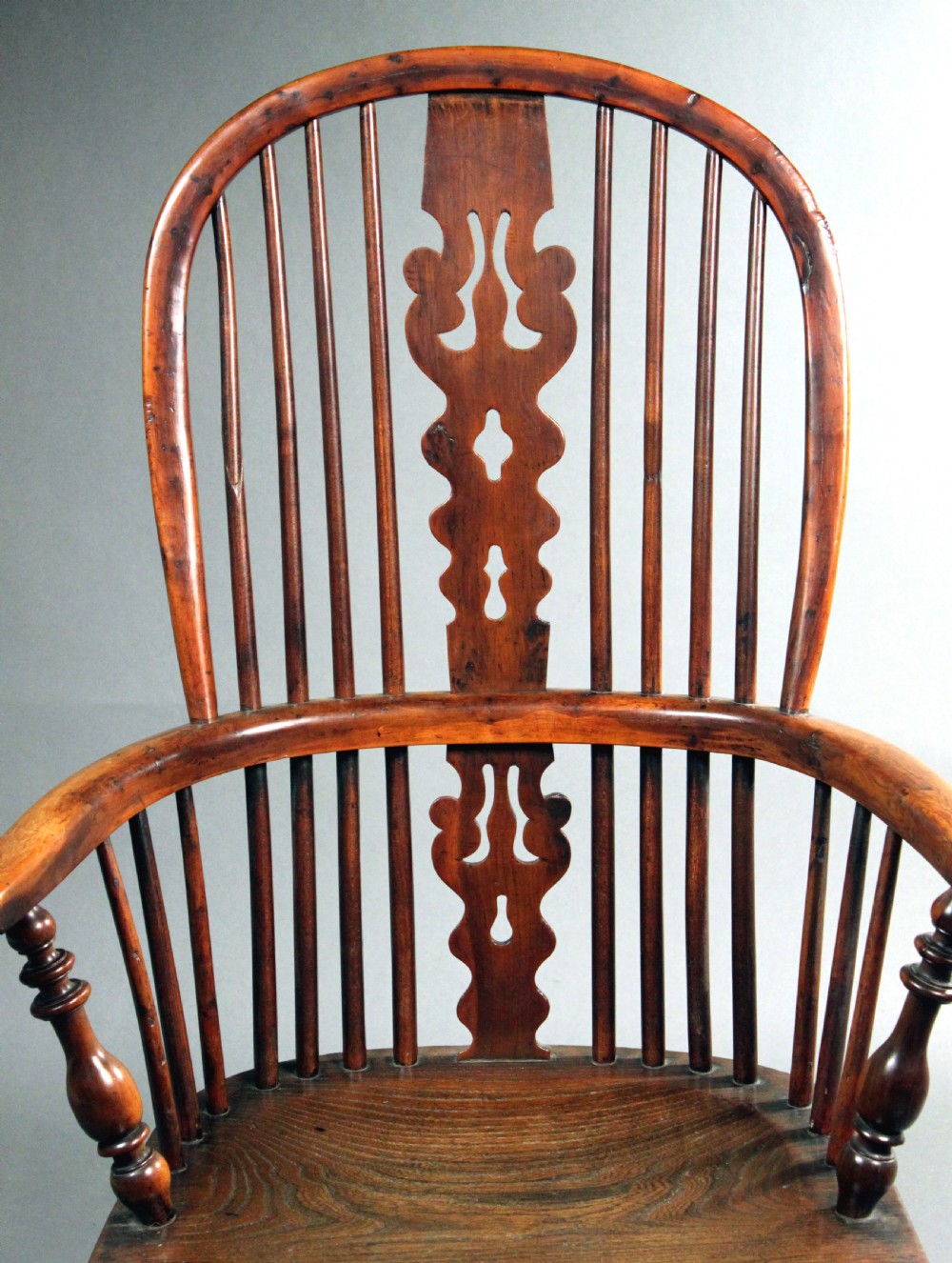 An antique yew wood Windsor armchair featuring a high bow back with vertical spindles, a pierced central splat, turned arm supports, and a shaped seat. View IV