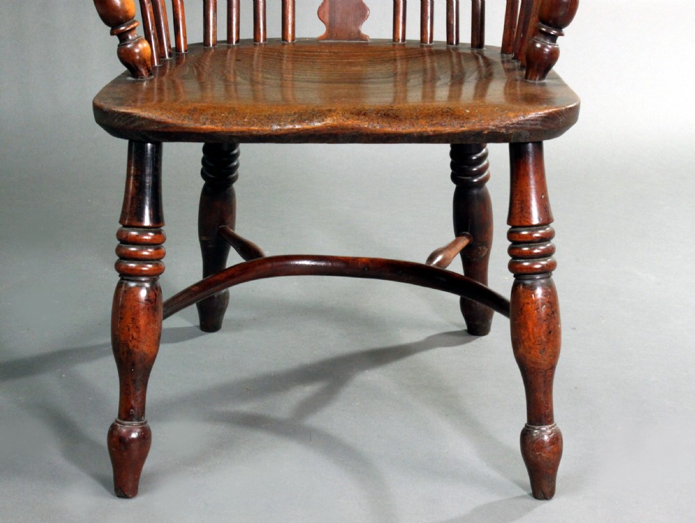 An antique yew wood Windsor armchair featuring a high bow back with vertical spindles, a pierced central splat, turned arm supports, and a shaped seat. View VI