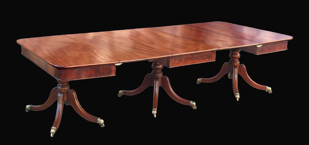 A long Regency-style mahogany extension dining table featuring three turned pedestal bases on brass cap castors. View III