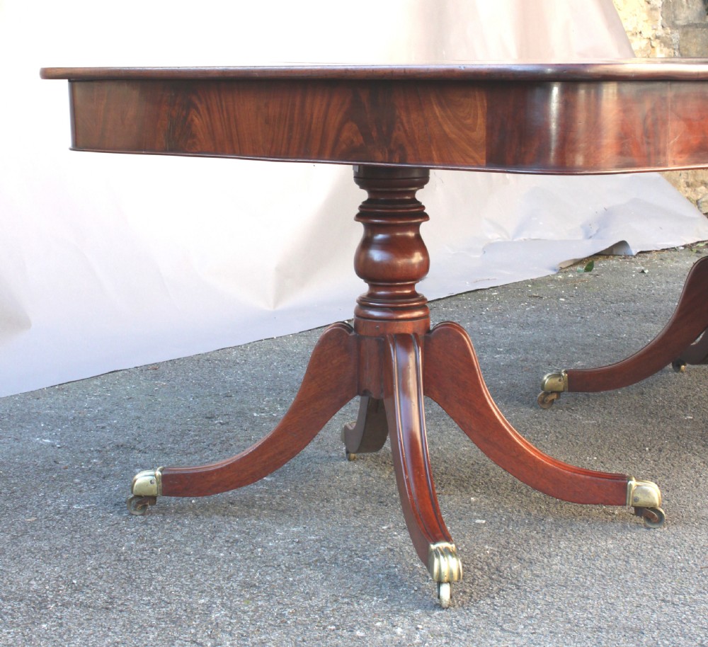 A long Regency-style mahogany extension dining table featuring three turned pedestal bases on brass cap castors. View V