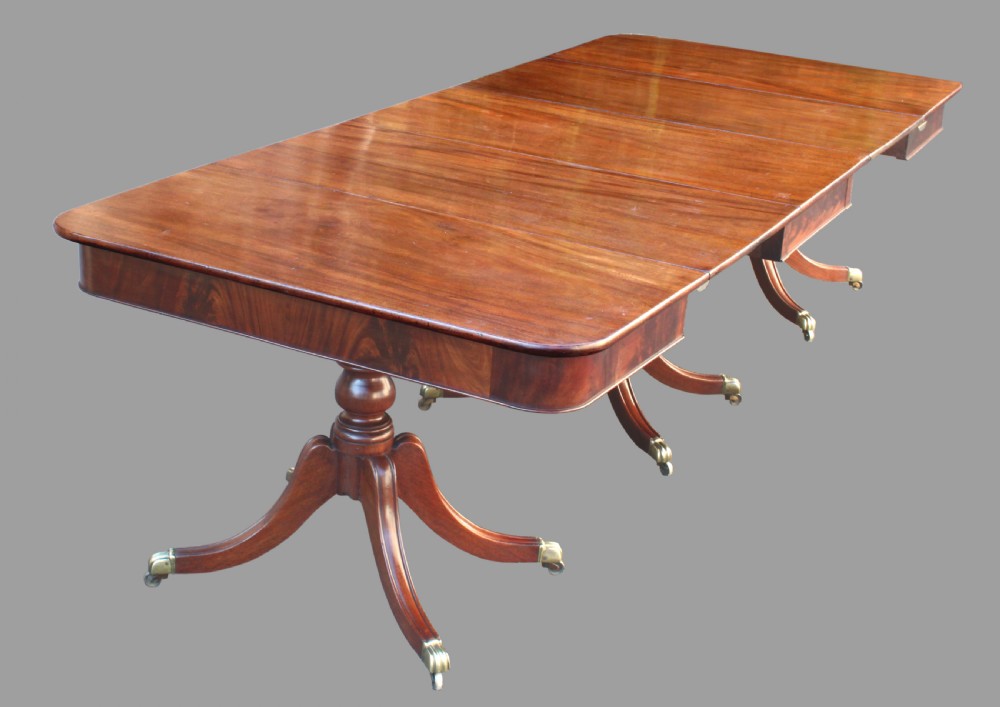A long Regency-style mahogany extension dining table featuring three turned pedestal bases on brass cap castors. View VII
