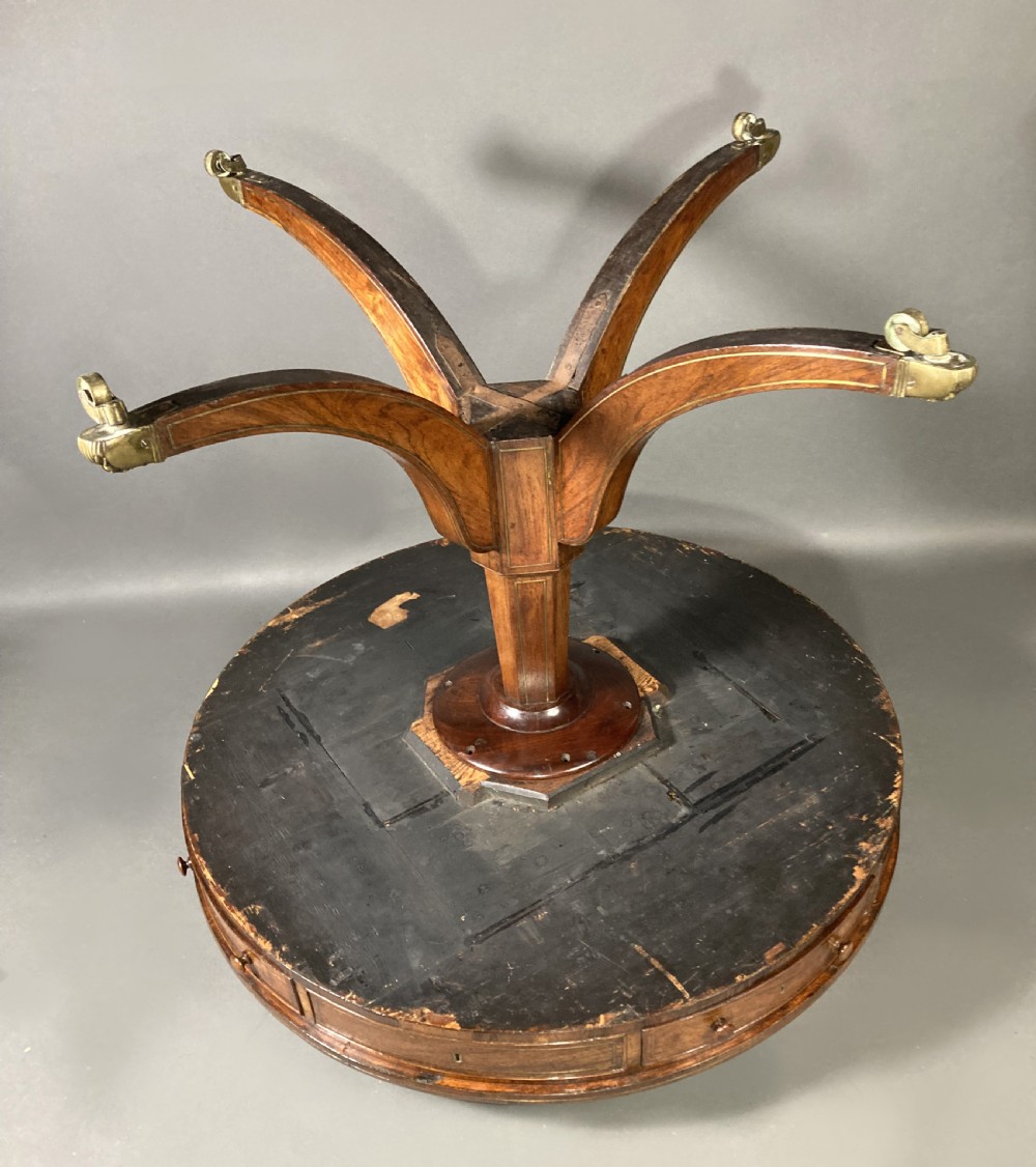 A circular Regency rosewood drum table with a green leather top, frieze drawers, and a central pedestal resting on four splayed legs with brass castors. View IX