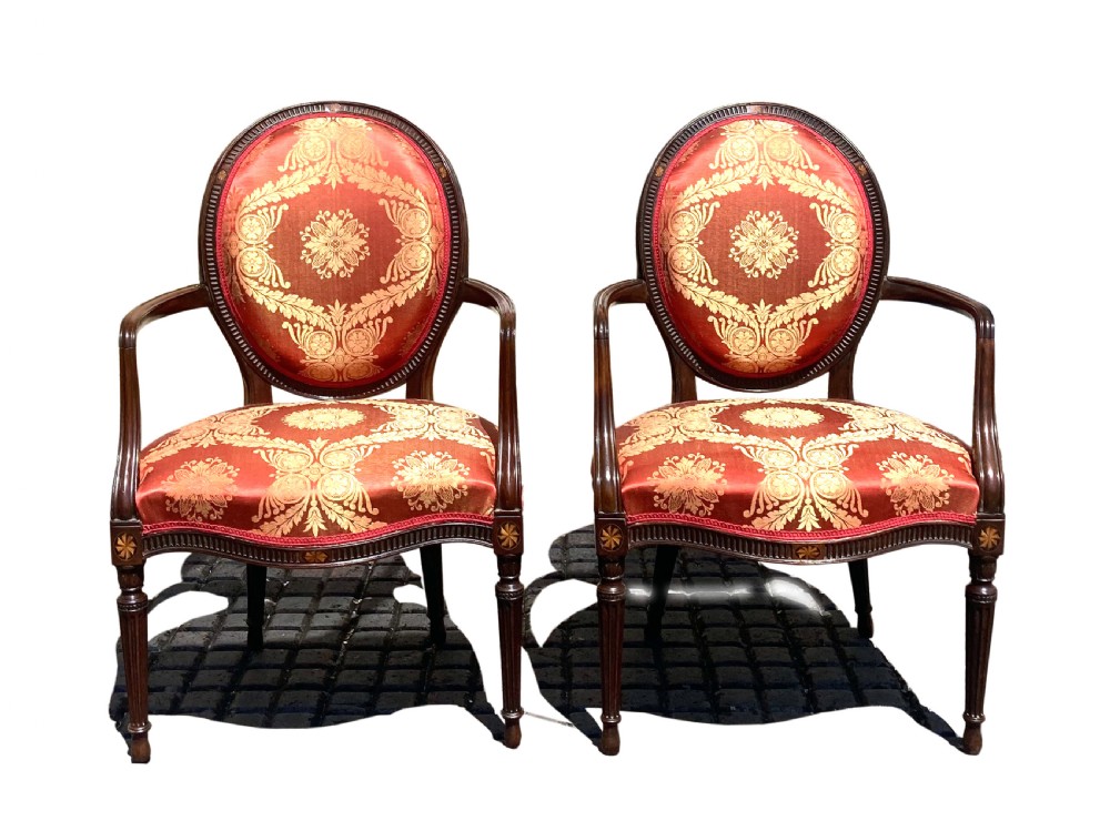 A pair of antique George III mahogany armchairs featuring oval backs and patterned red and gold damask upholstery. View IV