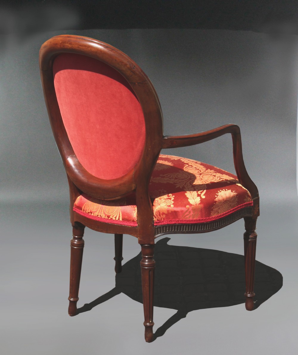 A pair of antique George III mahogany armchairs featuring oval backs and patterned red and gold damask upholstery. View V