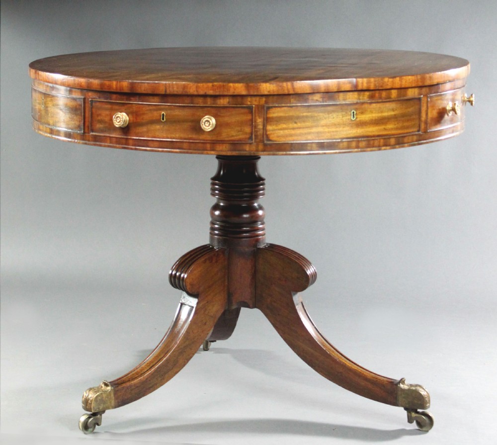 A circular Regency mahogany drum table featuring a deep drawer frieze on a turned central pedestal with four splayed legs and brass castors. View II