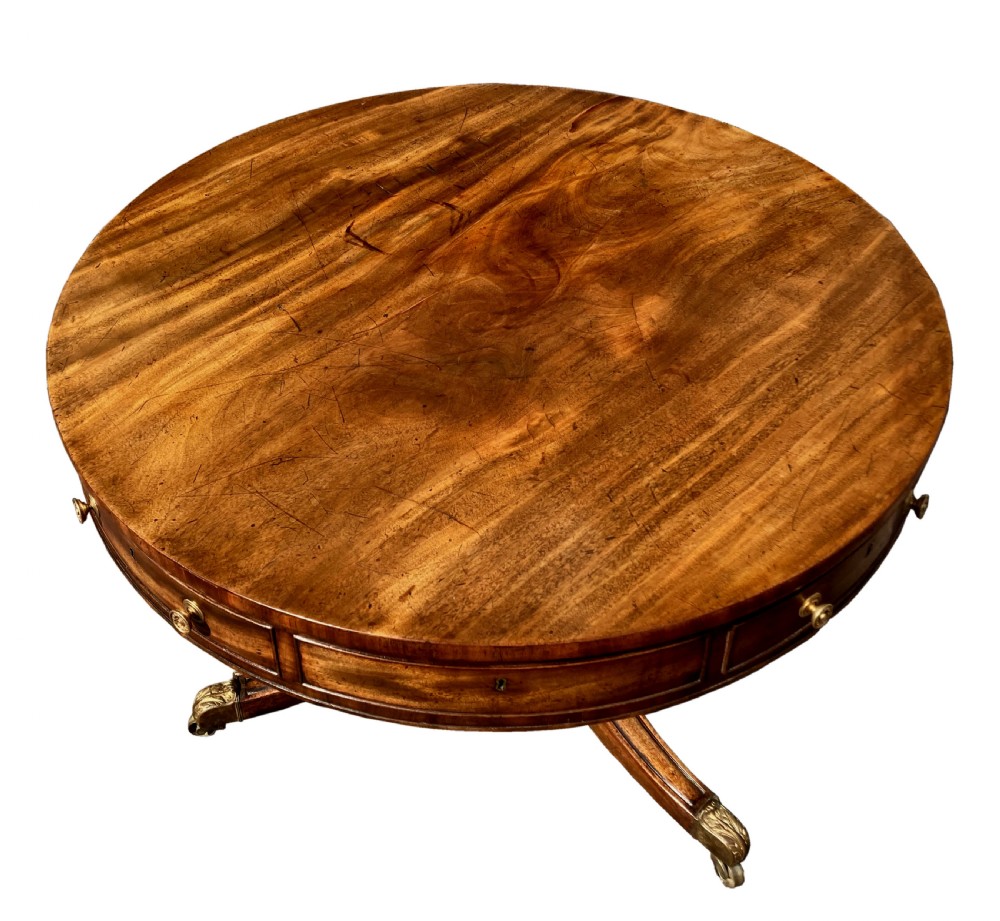 A circular Regency mahogany drum table featuring a deep drawer frieze on a turned central pedestal with four splayed legs and brass castors. View III