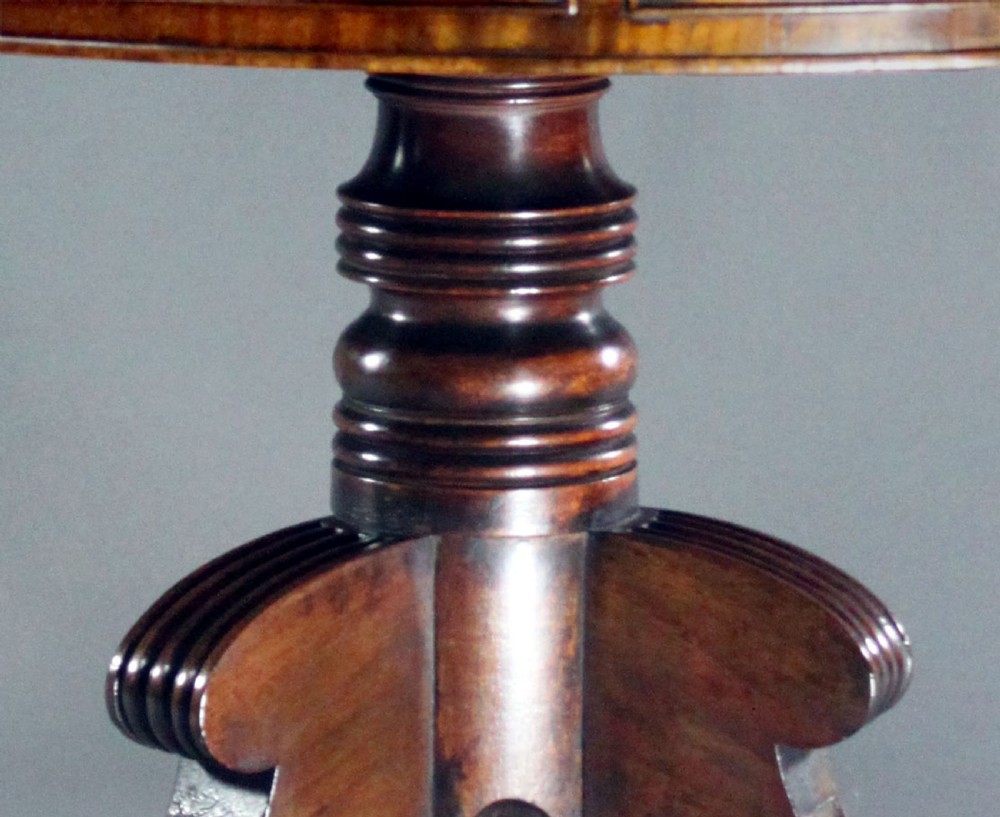 A circular Regency mahogany drum table featuring a deep drawer frieze on a turned central pedestal with four splayed legs and brass castors. View VIII