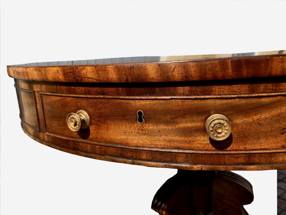 A circular Regency mahogany drum table featuring a deep drawer frieze on a turned central pedestal with four splayed legs and brass castors. View X