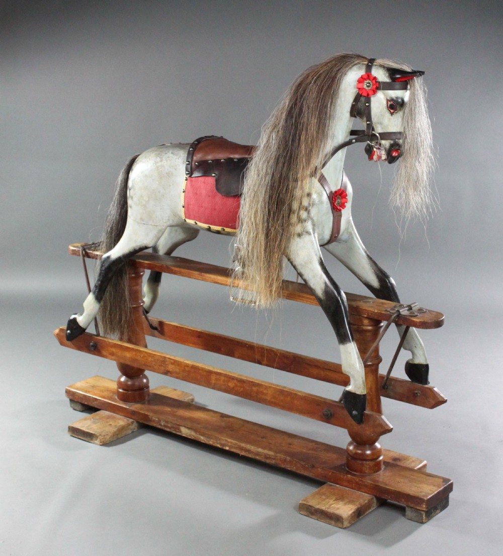 A 19th-century carved wooden dapple grey rocking horse mounted on a stained timber safety glider stand with leather tack and a natural horsehair mane. View II
