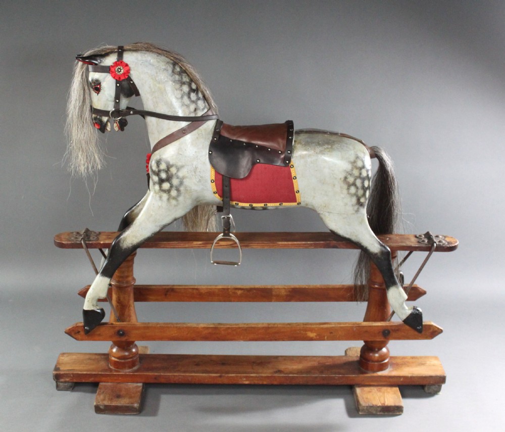 A 19th-century carved wooden dapple grey rocking horse mounted on a stained timber safety glider stand with leather tack and a natural horsehair mane. View VI