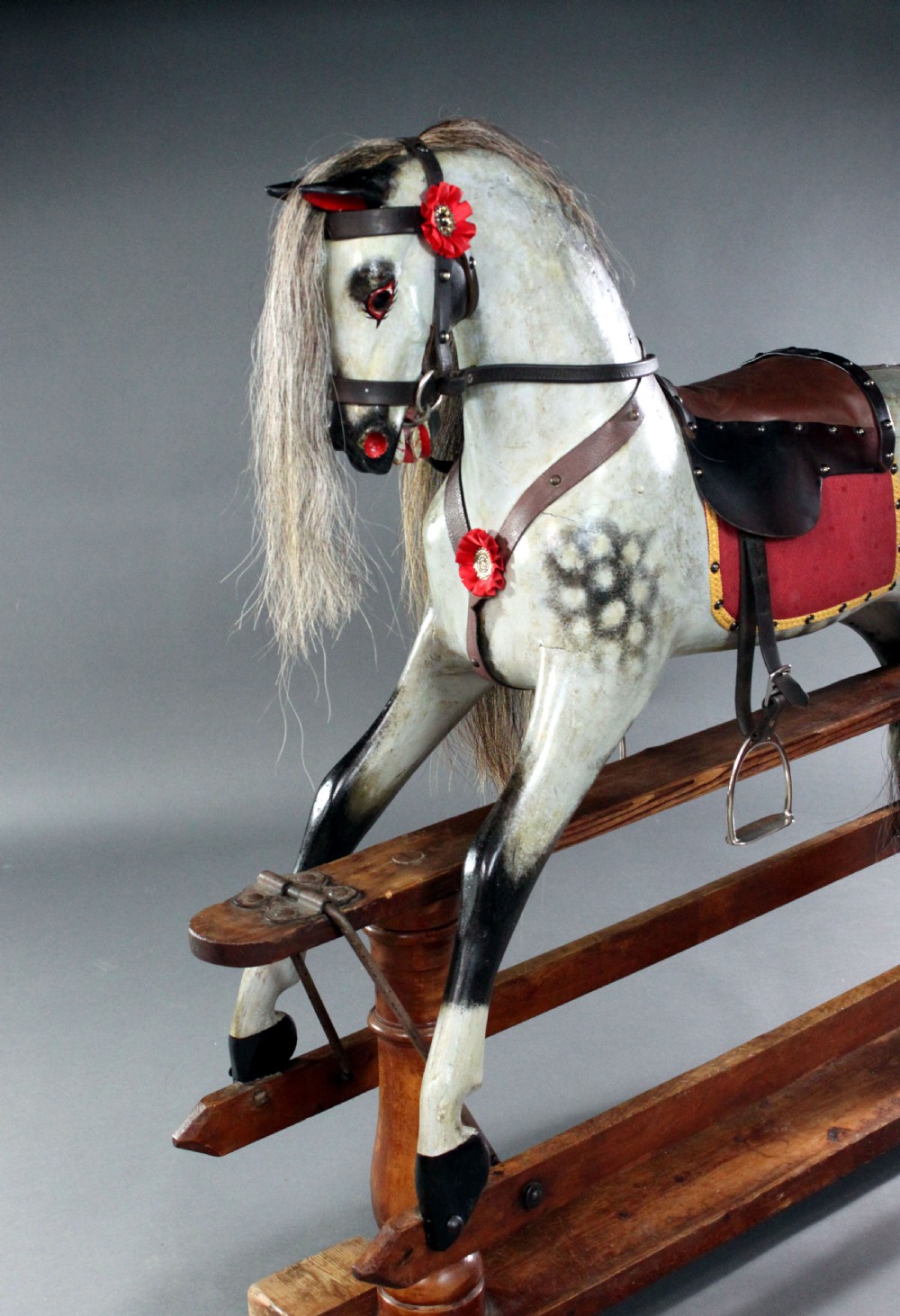 A 19th-century carved wooden dapple grey rocking horse mounted on a stained timber safety glider stand with leather tack and a natural horsehair mane. View VII
