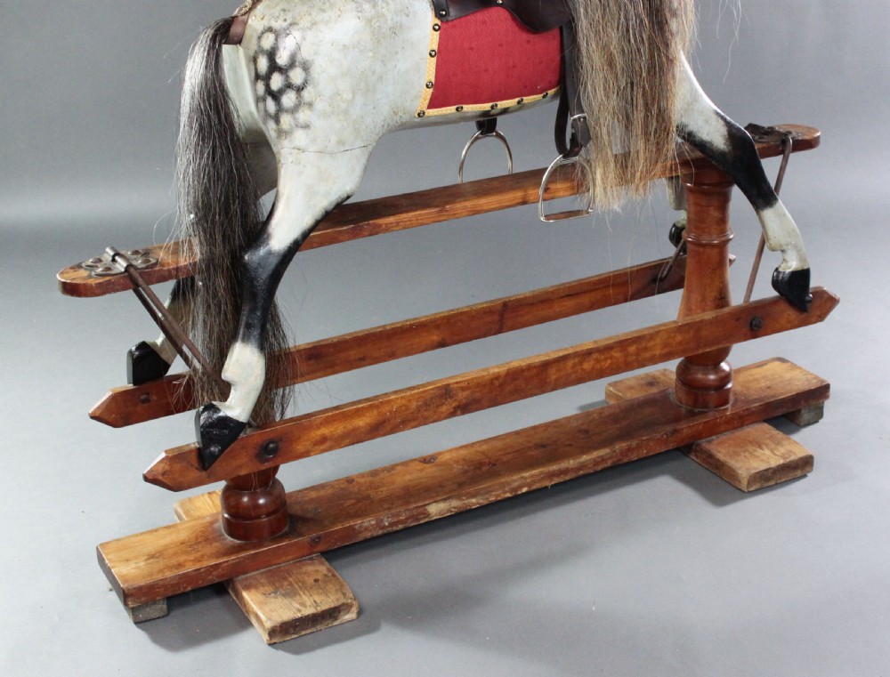 A 19th-century carved wooden dapple grey rocking horse mounted on a stained timber safety glider stand with leather tack and a natural horsehair mane. View VIII