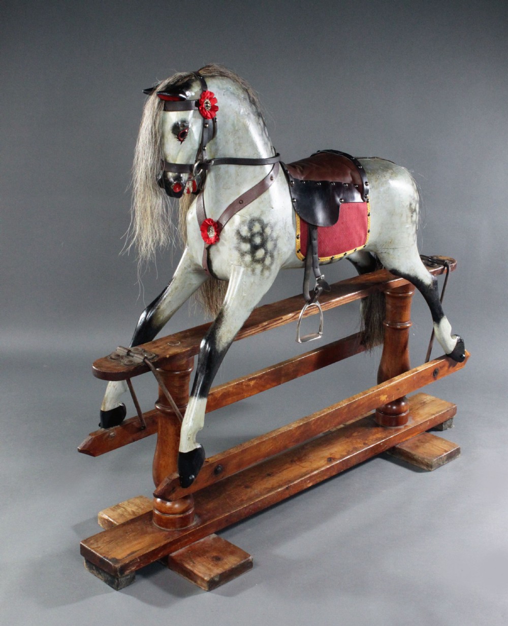 A 19th-century carved wooden dapple grey rocking horse mounted on a stained timber safety glider stand with leather tack and a natural horsehair mane. View IX