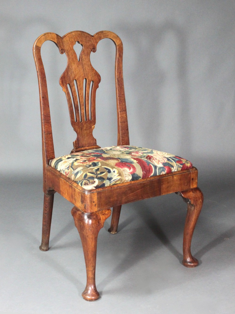 A pair of 18th-century George II walnut side chairs featuring pierced vase-shaped splats, floral upholstered drop-in seats, and front cabriole legs. View V