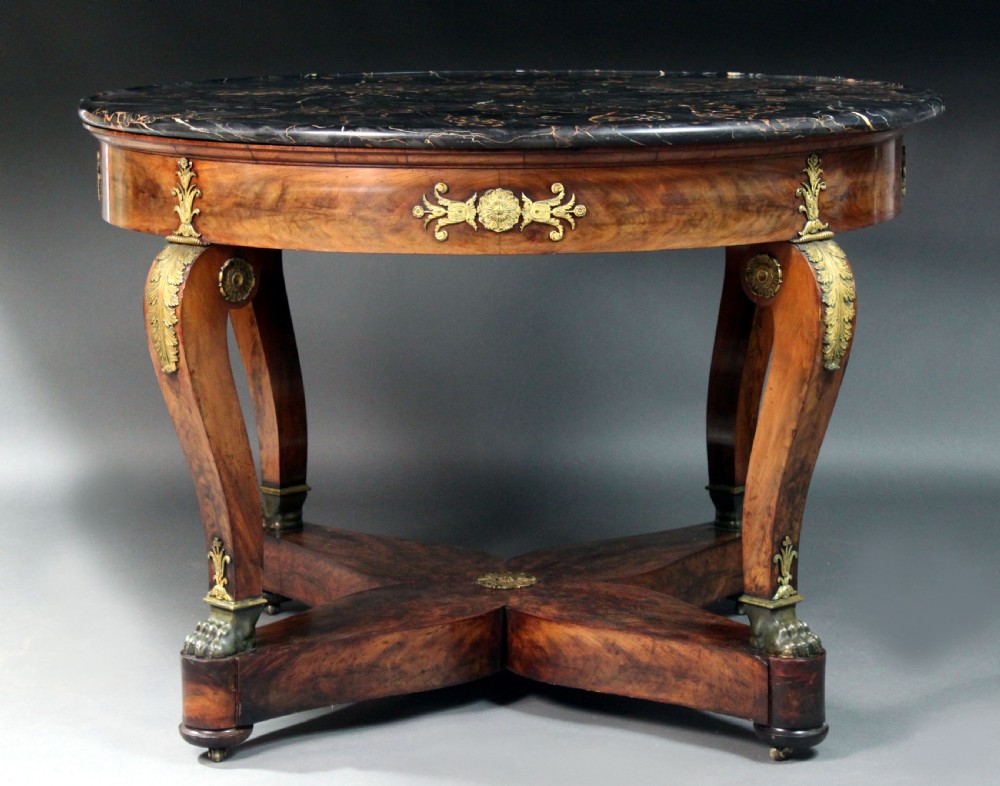 A circular French Empire centre table featuring a black veined marble top, mahogany apron with gilt bronze mounts, and curved legs on a cruciform base. View IV