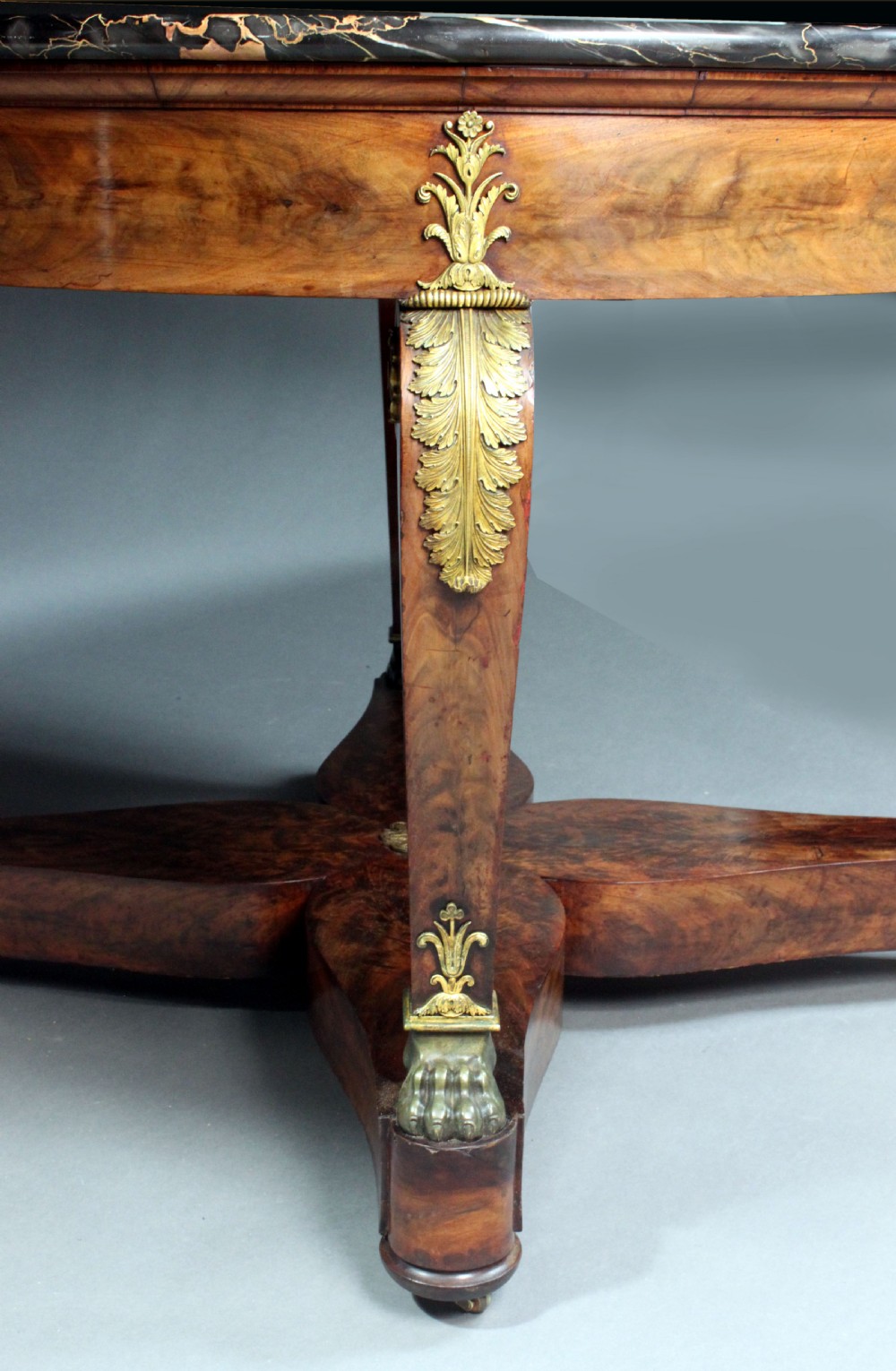 A circular French Empire centre table featuring a black veined marble top, mahogany apron with gilt bronze mounts, and curved legs on a cruciform base. View VIII