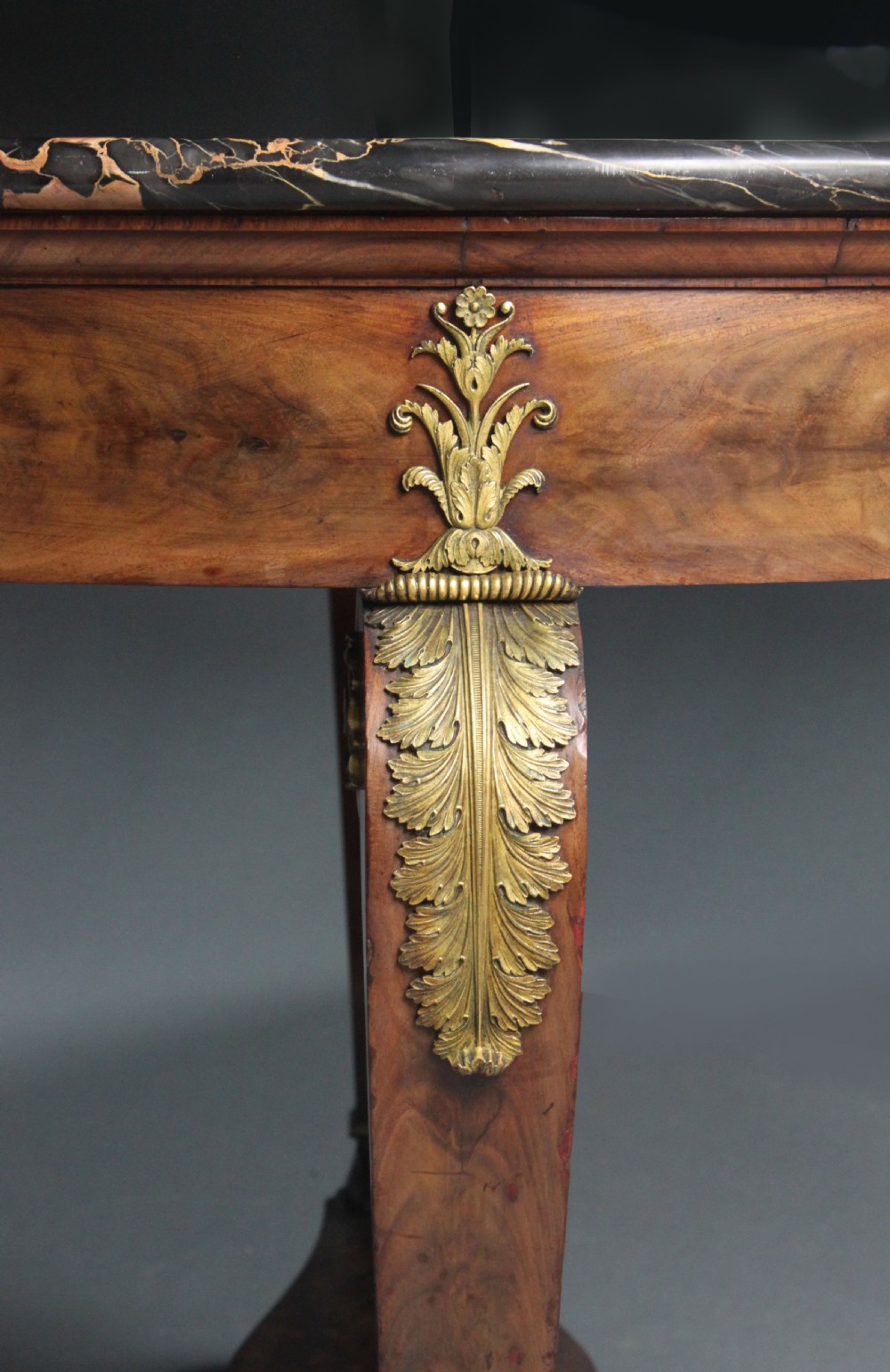 A circular French Empire centre table featuring a black veined marble top, mahogany apron with gilt bronze mounts, and curved legs on a cruciform base. View X
