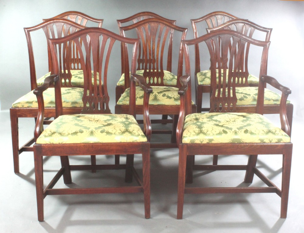 A set of eight Georgian mahogany dining chairs featuring carved pierced back splats and green damask upholstered seats, including six side chairs and two armchairs.