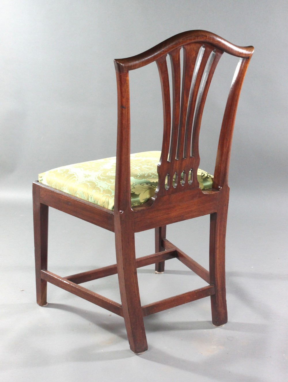 A set of eight Georgian mahogany dining chairs featuring carved pierced back splats and green damask upholstered seats, including six side chairs and two armchairs. View VI