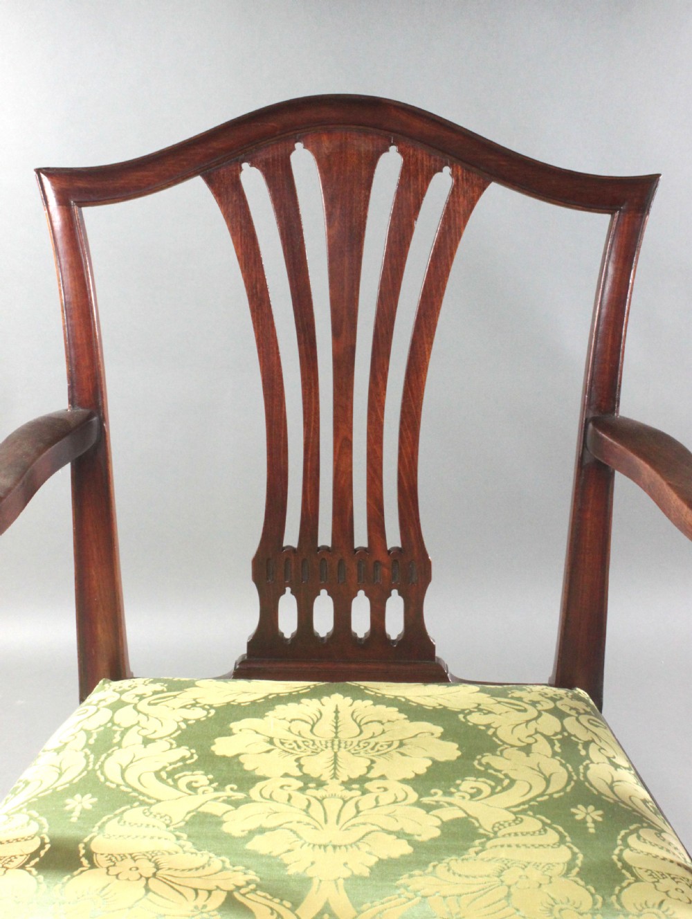 A set of eight Georgian mahogany dining chairs featuring carved pierced back splats and green damask upholstered seats, including six side chairs and two armchairs. View VIII