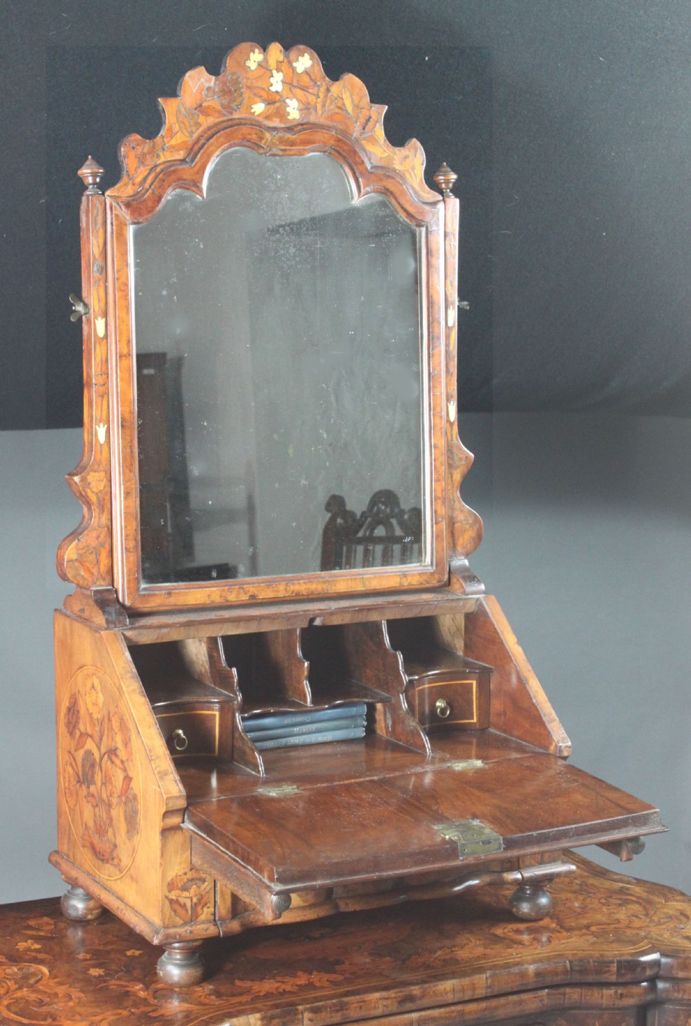 An antique Dutch walnut toilet mirror featuring detailed floral marquetry inlay, an arched frame, and a slant-front drawer base supported by bun feet. View III