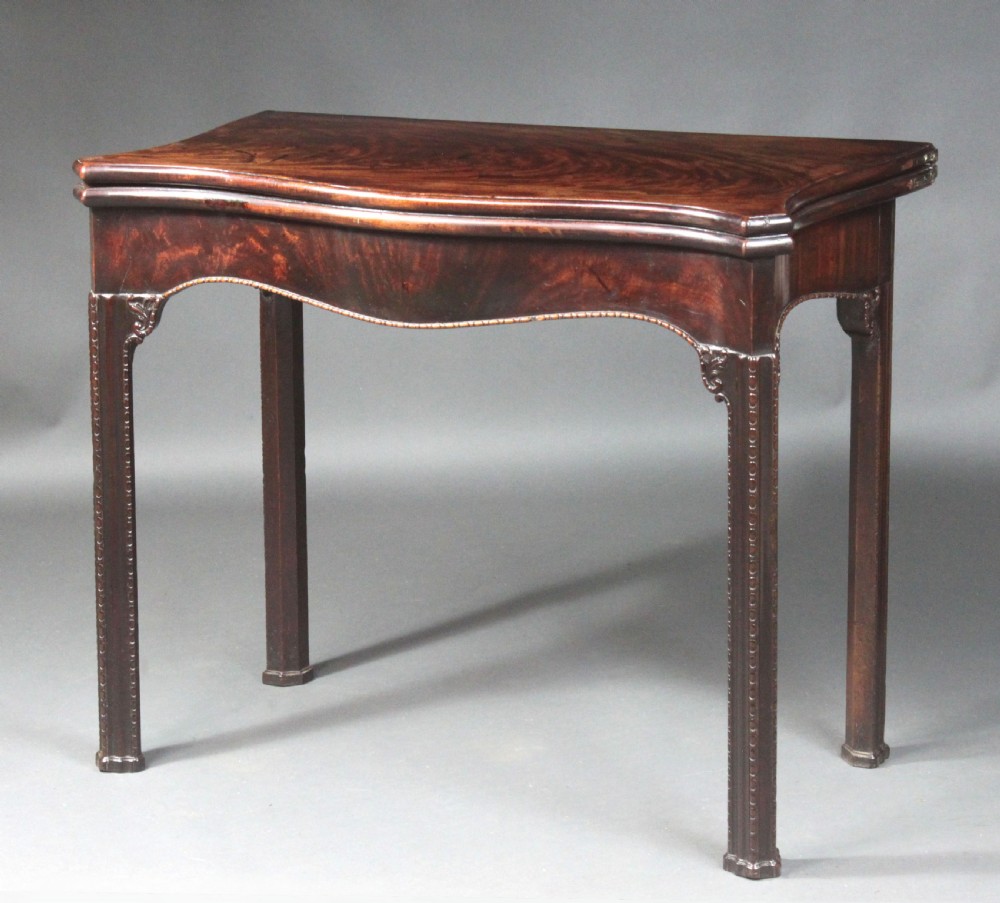 An 18th-century Chippendale style mahogany card table featuring a serpentine fold-over top, carved apron edge, and square moulded legs. View II