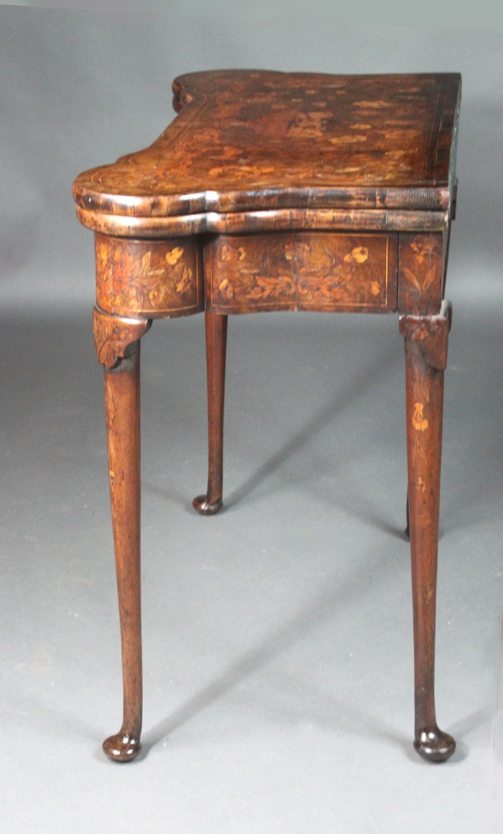 An antique Dutch walnut card table featuring detailed floral marquetry inlay, a serpentine frieze with a single drawer, and slender legs. View IX