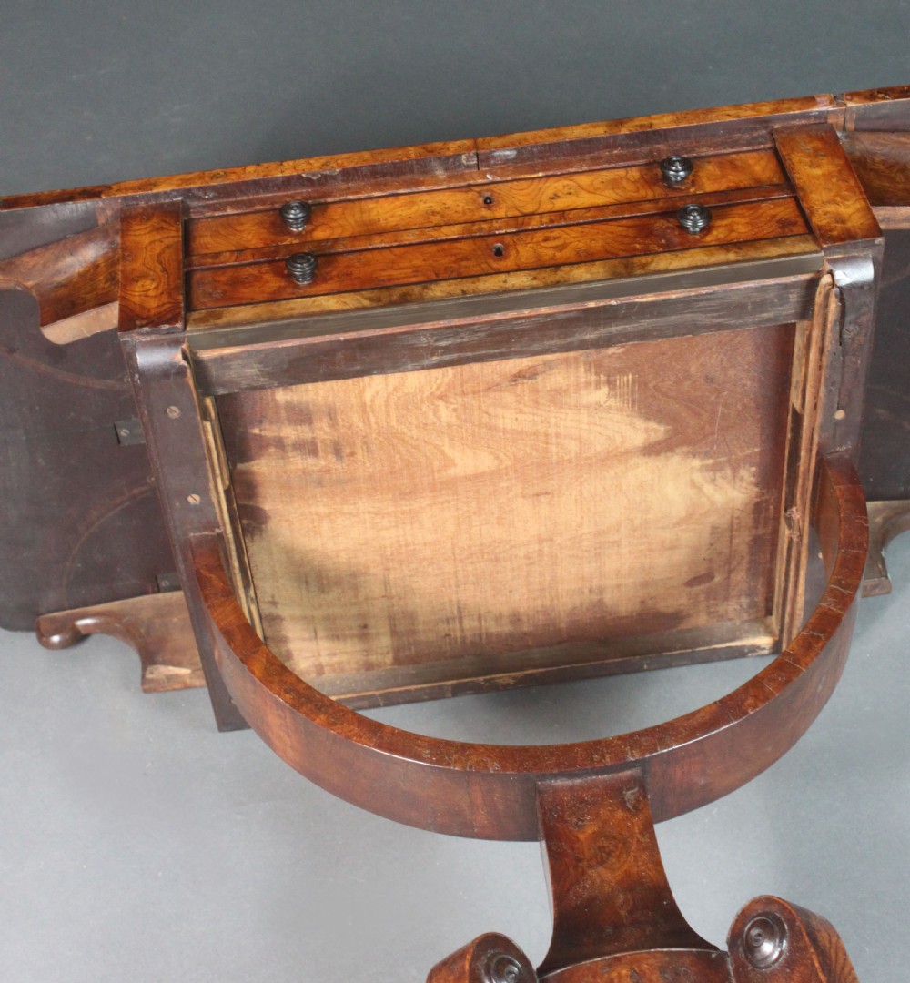 A Regency period burr ash work table featuring drop leaves, two small drawers with round knobs, a U-shaped pedestal support, and four splayed legs with brass castors. View XI