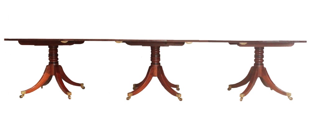A long Regency mahogany dining table supported by three central pedestal bases with splayed legs and brass castors. View III