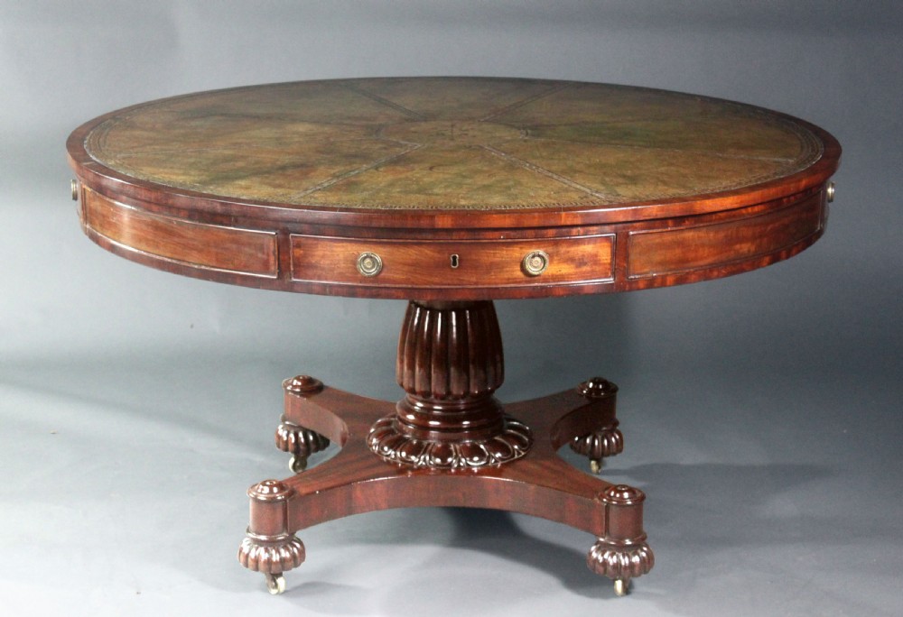 A circular Georgian mahogany drum table featuring a green leather inset top with gilt tooling, frieze drawers with brass handles, and a carved pedestal base resting on four splayed legs with castors. View IV
