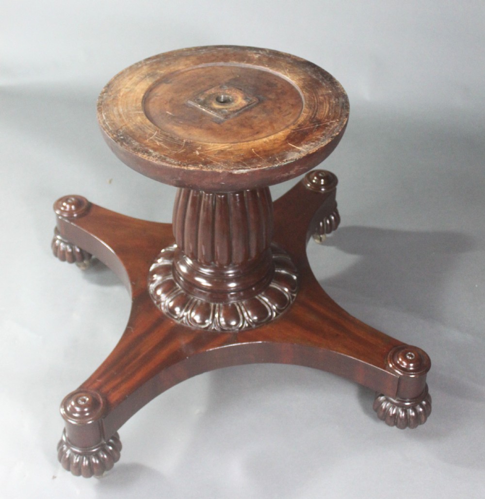 A circular Georgian mahogany drum table featuring a green leather inset top with gilt tooling, frieze drawers with brass handles, and a carved pedestal base resting on four splayed legs with castors. View V