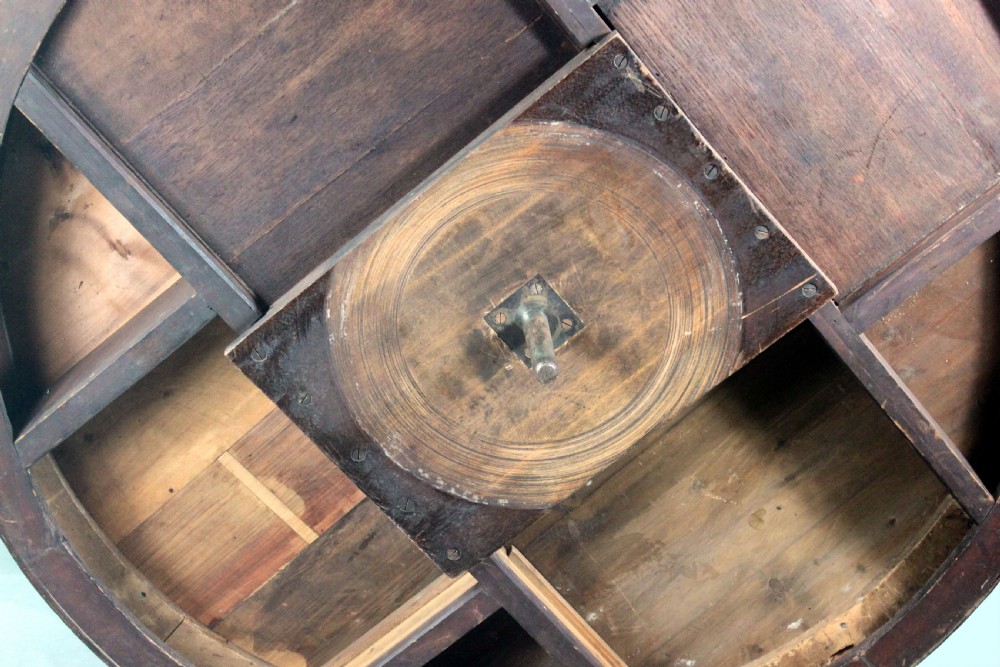 A circular Georgian mahogany drum table featuring a green leather inset top with gilt tooling, frieze drawers with brass handles, and a carved pedestal base resting on four splayed legs with castors. View X