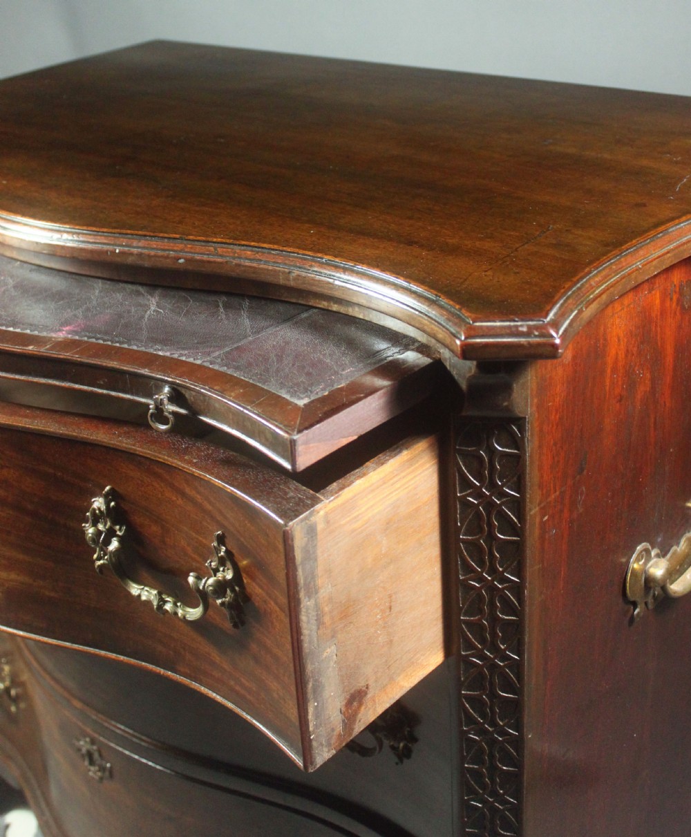 An eighteenth-century George III mahogany chest of drawers featuring a serpentine front, carved blind fretwork, brass handles, and bracket feet. View VI