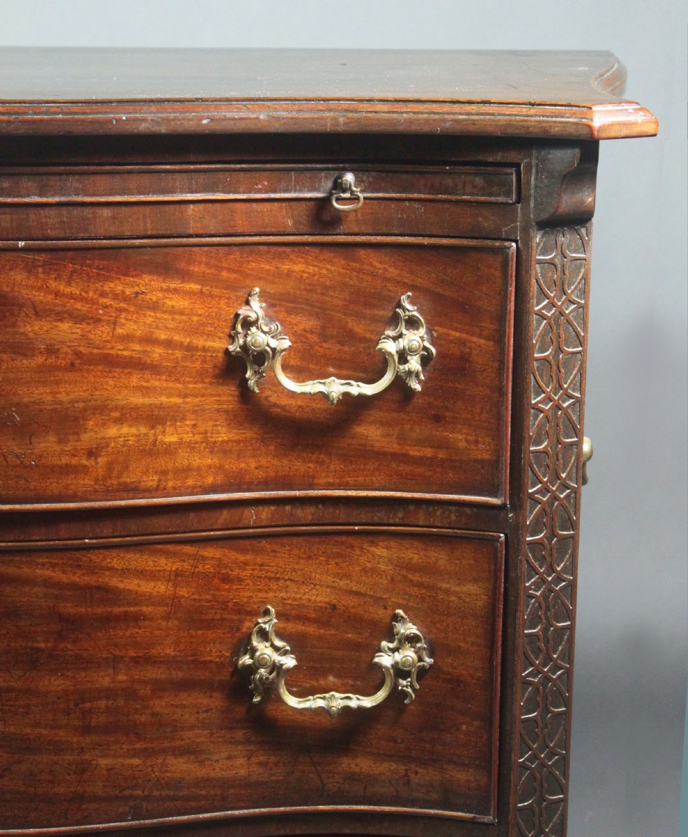 An eighteenth-century George III mahogany chest of drawers featuring a serpentine front, carved blind fretwork, brass handles, and bracket feet. View VII