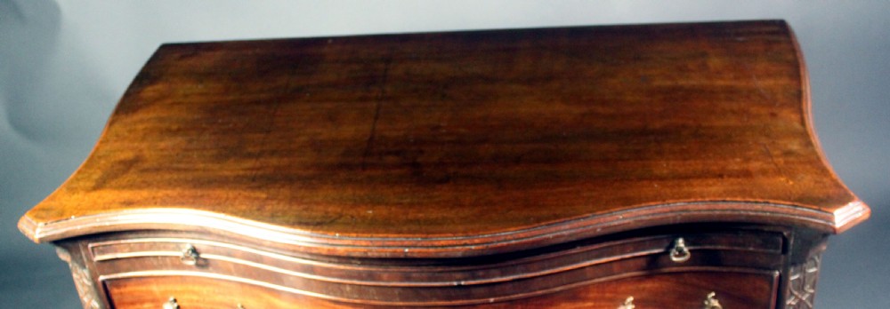 An eighteenth-century George III mahogany chest of drawers featuring a serpentine front, carved blind fretwork, brass handles, and bracket feet. View VIII