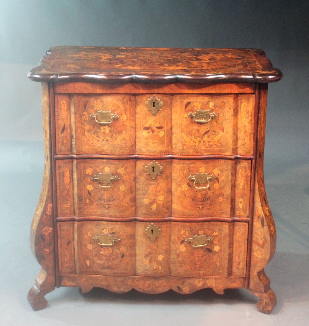 An antique Dutch marquetry chest of drawers featuring three drawers, floral wood inlay, shaped sides, and brass drop handles. View II