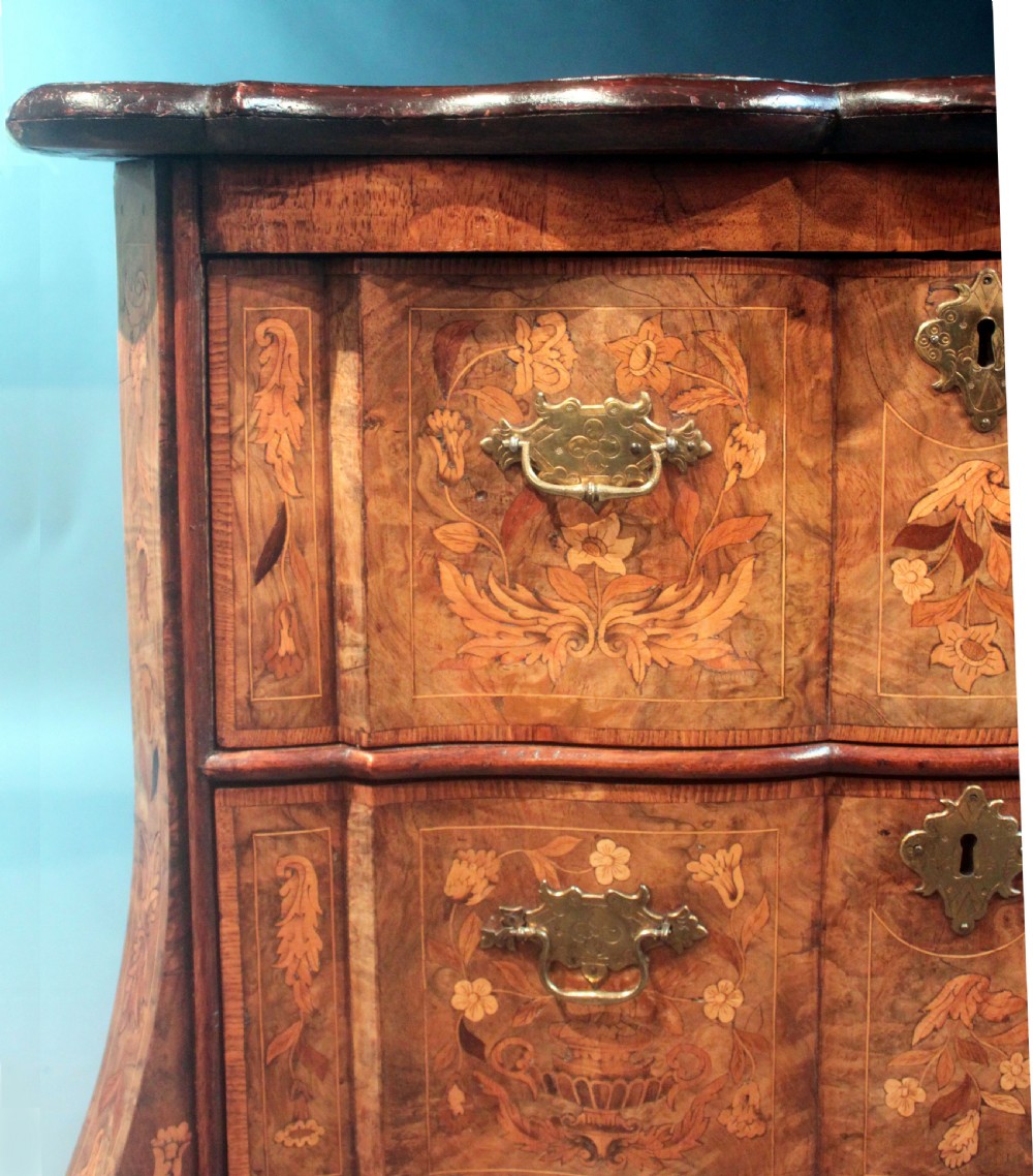 An antique Dutch marquetry chest of drawers featuring three drawers, floral wood inlay, shaped sides, and brass drop handles. View IX