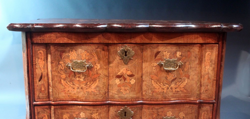 An antique Dutch marquetry chest of drawers featuring three drawers, floral wood inlay, shaped sides, and brass drop handles. View XI